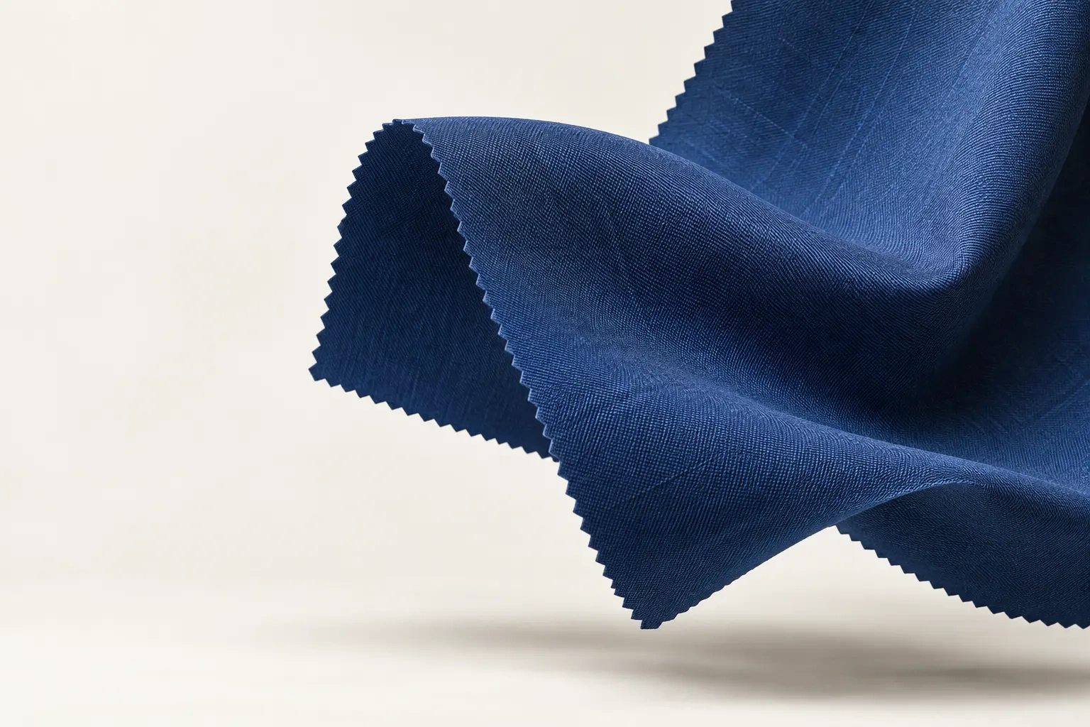 A length of cobalt wool suiting, its pinked edge lifted like a sail.